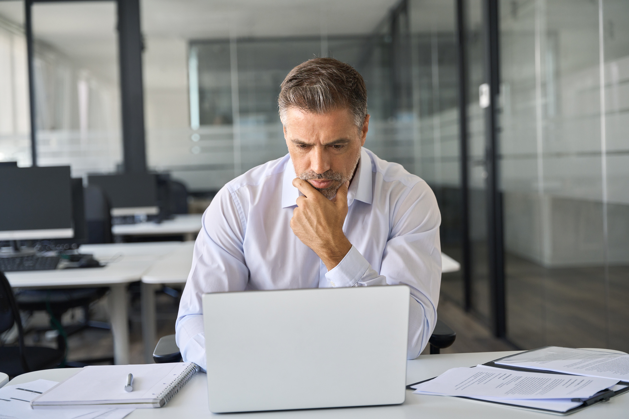 Serious busy business man ceo executive manager looking at laptop thinking.
