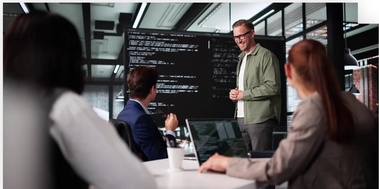 Developer presenting source code on a large screen to colleagues in a meeting-converted-from-png